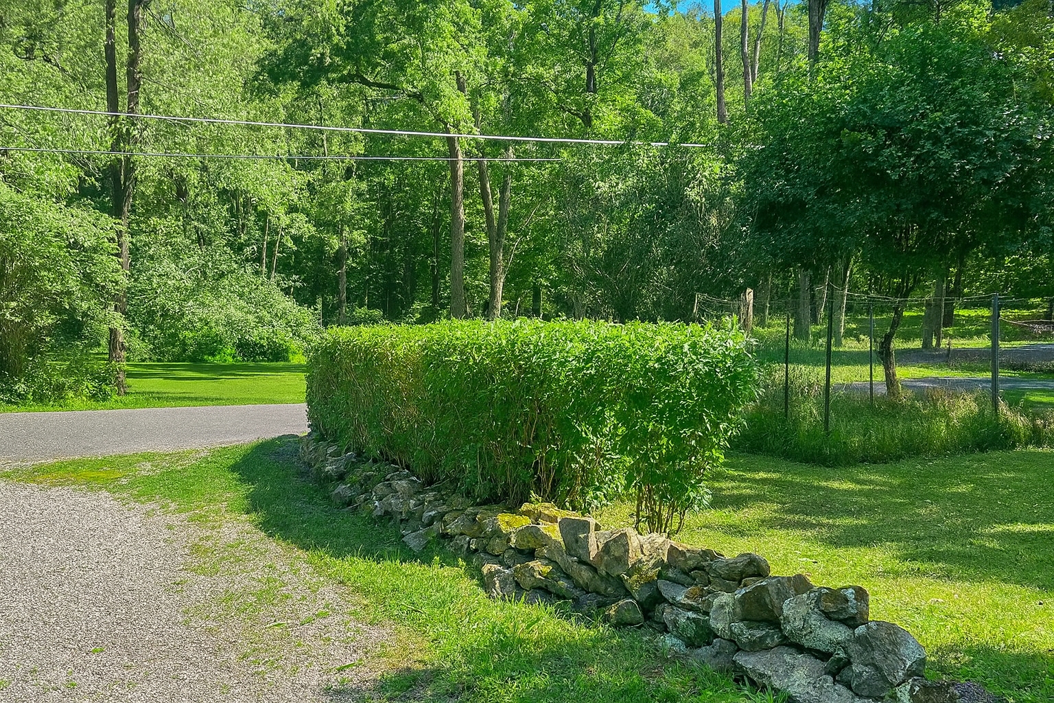 Well-maintained residential property with stone retaining wall, trimmed hedges, and professional landscaping